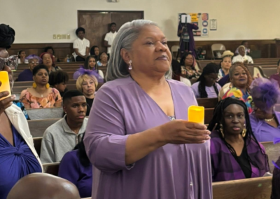 Members in shades of purple for Elders day. Two members in the front are holding candles to honor members who have passed.